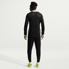 Ein Mann in schwarzer Sportkleidung mit weißem Kragen und gelben Fußballschuhen.