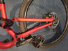 Detail der Hinterradaufhängung und des Pedals eines roten Mountainbikes.