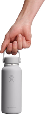Eine Hand hält eine graue Hydro Flask Flasche am Griff. Eine Hand hält eine graue Hydro Flask Flasche am Griff.
