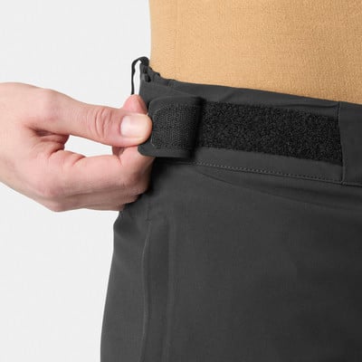 Eine Hand schließt einen Klettverschluss an dunklen Hosen. Eine Hand schließt einen Klettverschluss an dunklen Hosen.