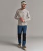 Ein Mann mit langärmeligem Shirt und blauen Hosen mit schwarzen Einsätzen, trägt Skischuhe.