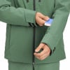 Mann verstaut Karte in den Ärmel einer grünen Jacke.