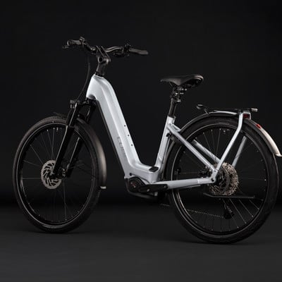 Ein silbernes E-Bike mit schwarzen Rädern und Schutzblechen vor dunklem Hintergrund. Ein silbernes E-Bike mit schwarzen Rädern und Schutzblechen vor dunklem Hintergrund.