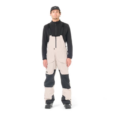 Mann in beige Latzhose und schwarzem Oberteil mit Mütze. Mann in beige Latzhose und schwarzem Oberteil mit Mütze.