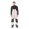 Mann in beige Latzhose und schwarzem Oberteil mit Mütze.