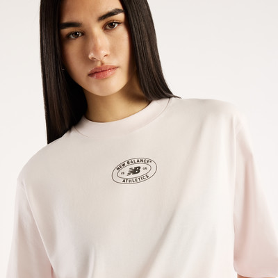 Frau in einem rosa T-Shirt mit New Balance Athletics Logo.
