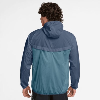 Rückansicht eines Mannes in einer blauen Windjacke mit Kapuze und Kontrastpaneelen.