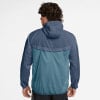 Rückansicht eines Mannes in einer blauen Windjacke mit Kapuze und Kontrastpaneelen.