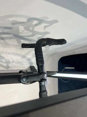 Ein schwarzer Fahrradlenker mit umwickeltem Lenkerband und Schatten von Radfahrern an der Wand. Ein schwarzer Fahrradlenker mit umwickeltem Lenkerband und Schatten von Radfahrern an der Wand.