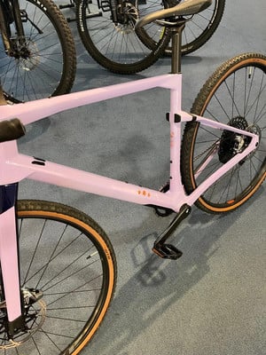 Lila Fahrrad mit schwarzen Details und braunen Reifen auf blauem Teppich. Lila Fahrrad mit schwarzen Details und braunen Reifen auf blauem Teppich.