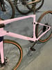 Lila Fahrrad mit schwarzen Details und braunen Reifen auf blauem Teppich.