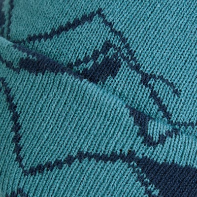 Detail einer Strickware mit dunkelblauem Karomuster auf türkisfarbenem Grund. Detail einer Strickware mit dunkelblauem Karomuster auf türkisfarbenem Grund.