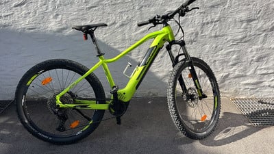 Ein grünes Elektro-Mountainbike, das an einer weißen Wand parkt. Ein grünes Elektro-Mountainbike, das an einer weißen Wand parkt.