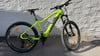 Ein grünes Elektro-Mountainbike, das an einer weißen Wand parkt.
