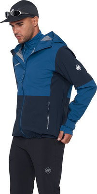 Ein Mann in einer dunklen Kapuzenjacke und Sonnenbrille auf einer Kappe.