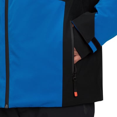 Blaue Jacke mit schwarzen Details und einer Reißverschlusstasche, in die jemand seine Hand steckt. Blaue Jacke mit schwarzen Details und einer Reißverschlusstasche, in die jemand seine Hand steckt.