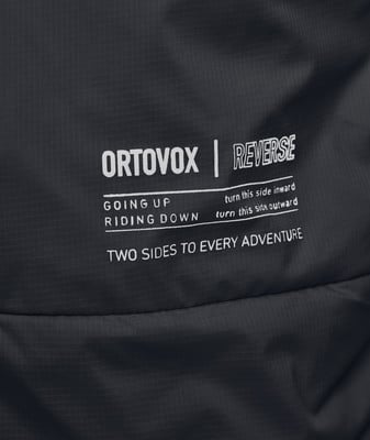 Detail des ORTOVOX-Logos und der Aufschrift REVERSE auf dunklem Material. Detail des ORTOVOX-Logos und der Aufschrift REVERSE auf dunklem Material.
