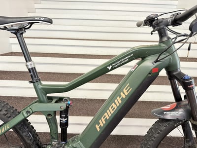 Ein grünes Haibike E-Bike mit Federung und Schriftzug auf dem Rahmen. Ein grünes Haibike E-Bike mit Federung und Schriftzug auf dem Rahmen.