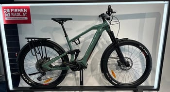 Grünes E-Bike mit Schutzblechen und Gepäckträger auf einem Ständer.