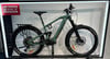 Grünes E-Bike mit Schutzblechen und Gepäckträger auf einem Ständer.