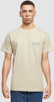 Mann in einem beigefarbenen T-Shirt mit Aufdruck auf der Brust. Mann in einem beigefarbenen T-Shirt mit Aufdruck auf der Brust.