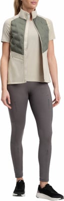 Frau in beige T-Shirt, gesteppter Weste und grauer Leggings. Frau in beige T-Shirt, gesteppter Weste und grauer Leggings.