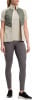 Frau in beige T-Shirt, gesteppter Weste und grauer Leggings.
