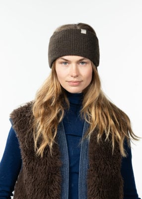 Eine Frau mit einer braunen Mütze und einer pelzigen Weste trägt einen blauen Rollkragenpullover. Eine Frau mit einer braunen Mütze und einer pelzigen Weste trägt einen blauen Rollkragenpullover.