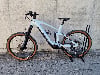 Ein hellblaues E-Bike mit braunen Reifen steht auf einem Ständer vor einer Wand.