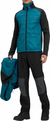 Ein Mann hält eine Jacke, trägt eine gesteppte Jacke und schwarze Hose. Ein Mann hält eine Jacke, trägt eine gesteppte Jacke und schwarze Hose.