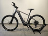 Graues Genesis E-Bike mit schwarzen Rädern und grünen Akzenten auf einem Ständer.