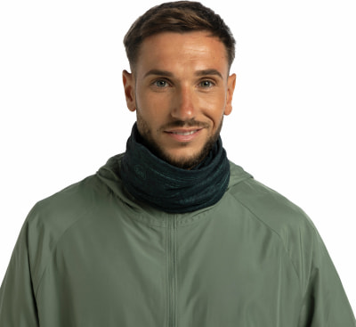 Ein Mann in einer grünen Jacke und einem dunkelgrünen Schlauchtuch lächelt.