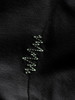 Detail eines schwarzen Stoffes mit einem feinen grünen Stickmuster, das an DNA erinnert.