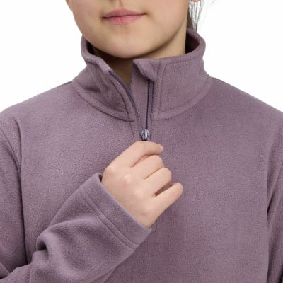 Ein Mädchen zupft am Reißverschluss eines violetten Fleece-Pullover mit hohem Kragen.