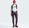 Frau in roter Mütze, Sonnenbrille, weißem Fleece und lila Leggings.