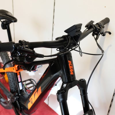 Schwarzes KTM E-Mountainbike mit orangefarbenen Details und Display. Schwarzes KTM E-Mountainbike mit orangefarbenen Details und Display.