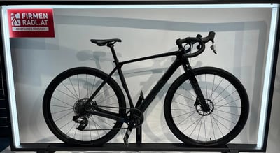 Ein schwarzes Gravelbike auf einem Ausstellungsständer mit Werbung Ein schwarzes Gravelbike auf einem Ausstellungsständer mit Werbung