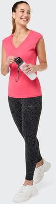 Eine Frau in einem pinken Shirt und Leggings mit Leopardenmuster hält eine Flasche. Eine Frau in einem pinken Shirt und Leggings mit Leopardenmuster hält eine Flasche.