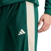 Grüne Trainingshose mit beige Streifen und Adidas Logo.