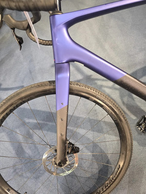 Detail des Rahmens und Vorderrads eines violetten Gravelbikes. Detail des Rahmens und Vorderrads eines violetten Gravelbikes.