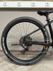 Hinterrad eines schwarzen Mountainbikes mit Federung und Schaltwerk.