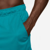 Detail eines Mannes in türkisfarbenen Shorts mit einer Hand in der Tasche.