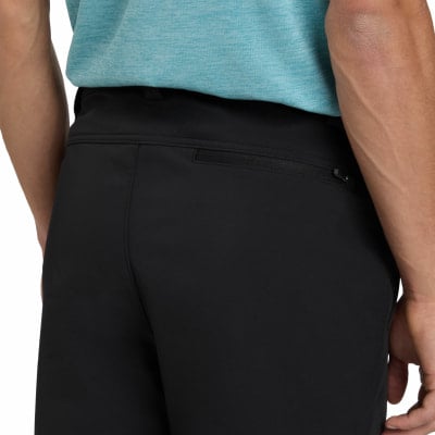 Detail der Gesäßtasche einer schwarzen Hose mit Reißverschluss und blauem Oberteil.