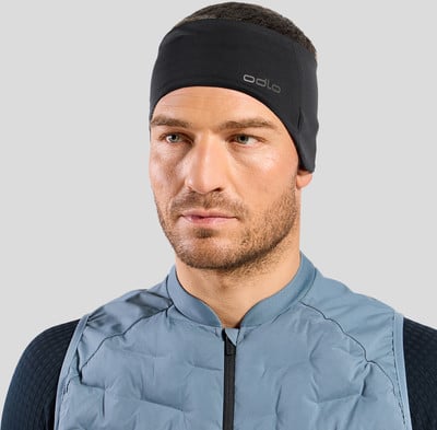 Ein Mann mit schwarzem Stirnband und blauer Weste vor grauem Hintergrund. Ein Mann mit schwarzem Stirnband und blauer Weste vor grauem Hintergrund.