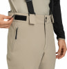 Nahaufnahme einer beige Hose mit schwarzen Hosenträgern und Reißverschlusstasche.
