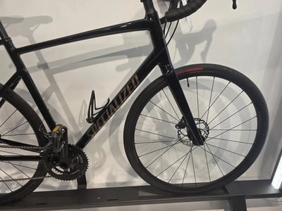Ein schwarzes Specialized Rennrad mit Scheibenbremsen auf einem Ständer. Ein schwarzes Specialized Rennrad mit Scheibenbremsen auf einem Ständer.