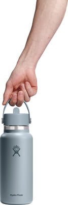 Eine Männerhand hält eine blaue Hydro Flask Flasche am Griff.