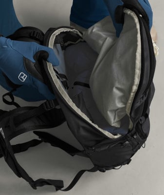 Eine Person zieht Handschuhe an und öffnet einen Rucksack, um etwas hineinzulegen. Eine Person zieht Handschuhe an und öffnet einen Rucksack, um etwas hineinzulegen.