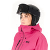 Eine Frau in einer rosa Jacke und einem Skhelm mit Brille blickt zur Seite.