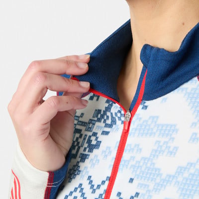 Detail des Kragenrands und Reißverschlusses einer weißen Jacke mit blauem Muster.